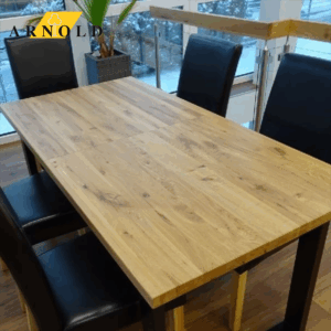 Sitzgarnitur bestehend aus dunklen Stühlen ohne Lehne und modernem Holztisch mit u-förmigem Fuß