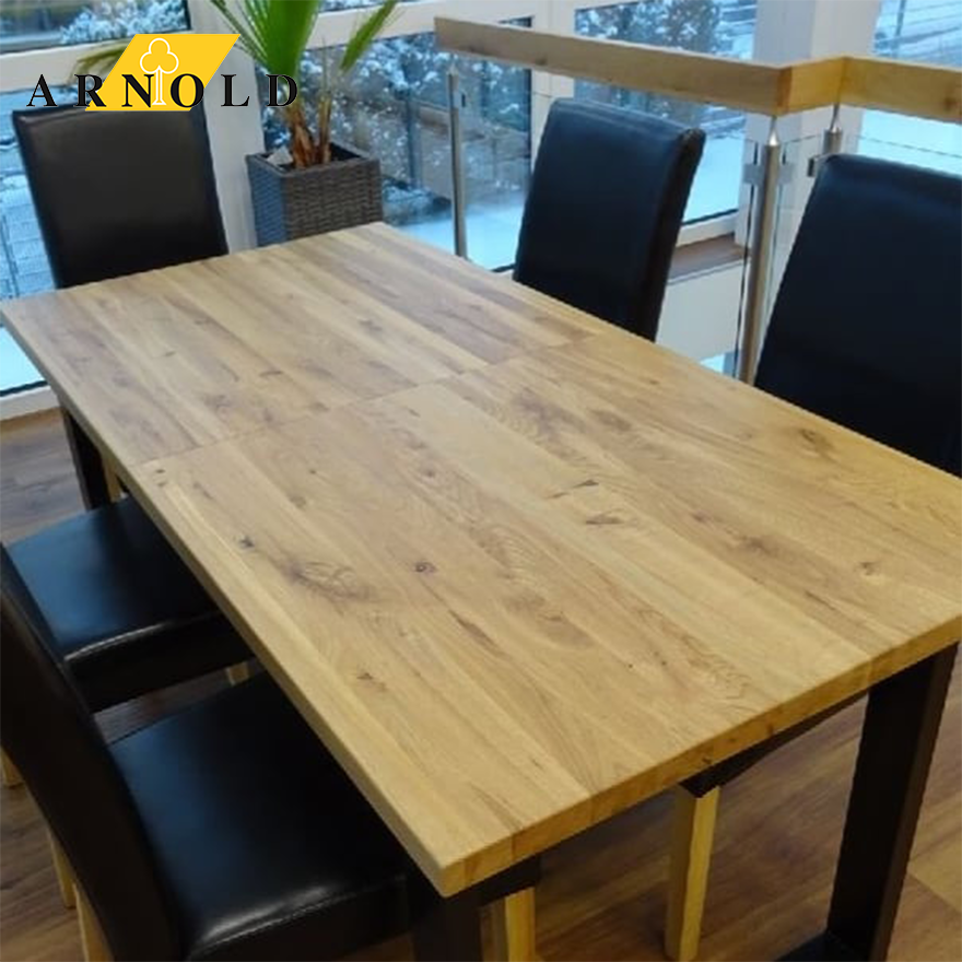 Sitzgarnitur bestehend aus dunklen Stühlen ohne Lehne und modernem Holztisch mit u-förmigem Fuß